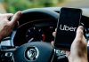 Person holding phone with Uber app inside car