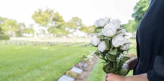 Person holding white roses at a cemetery