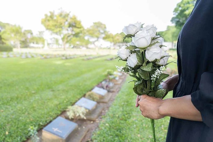 1569972004 featured image Person holding white roses at a cemetery
