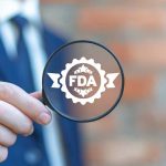 Person holding magnifying glass with FDA logo