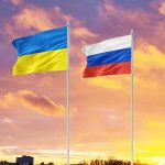 Ukrainian and Russian flags against a sunset background