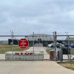 Chainlink fence with Restricted Area Stop No Photography sign