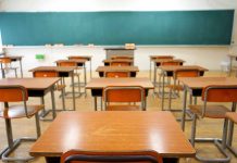 Classroom with wooden desks and empty green chalkboard