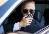 Man in suit using walkie-talkie in car