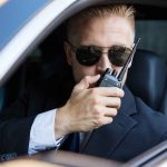 Man in suit using walkie-talkie in car