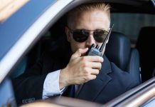 Man in suit using walkie-talkie in car