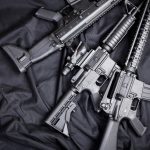 Assault rifles arranged on a black fabric background