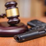 Gavel and handgun on a wooden surface