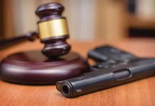 Gavel and handgun on a wooden surface