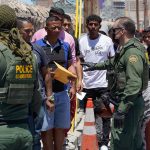 Border patrol agents inspecting group of individuals in line