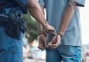 Police officer handcuffing person wearing blue clothes