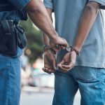 Police officer handcuffing person wearing blue clothes