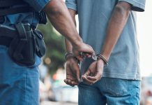 Police officer handcuffing person wearing blue clothes