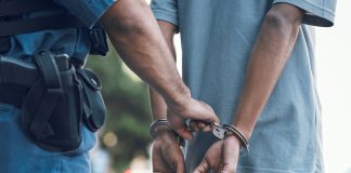 Police officer handcuffing person wearing blue clothes