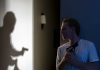 Man with gun watches shadow of armed figure