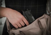 Hand placing handgun into beige handbag