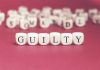 Dice spelling GUILTY on a red surface