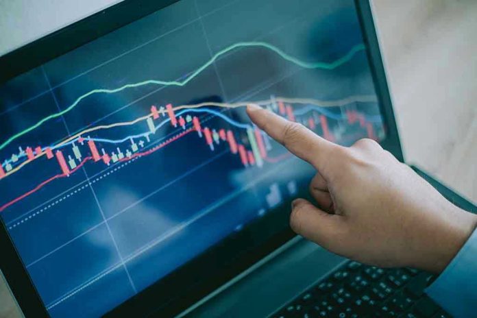 114313067 Hand pointing at stock market graph on laptop screen