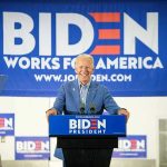 Man at podium with Biden campaign signs behind him