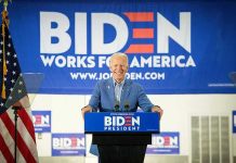 Man at podium with Biden campaign signs behind him