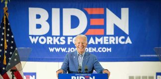 Man at podium with Biden campaign signs behind him