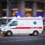 Ambulance driving on urban street with lights flashing