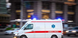 Ambulance driving on urban street with lights flashing