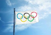 Olympic flag waving against a clear blue sky