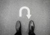 Feet in black shoes facing U turn road marking