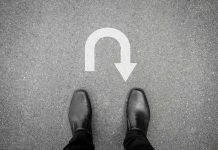 Feet in black shoes facing U turn road marking
