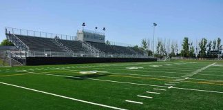 Empty football field with bleachers in background