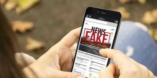 Person holding smartphone displaying fake news notification