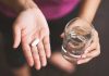 Person holding pill and glass of water