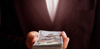 Hand holding a stack of hundred dollar bills