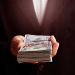 Hand holding a stack of hundred-dollar bills