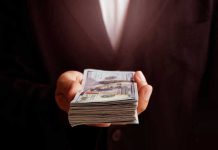 Hand holding a stack of hundred-dollar bills