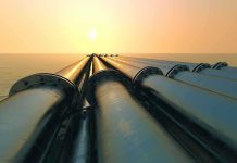 Industrial pipes extending towards the horizon over water during sunset