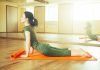 Woman practicing yoga on an orange mat in a bright studio