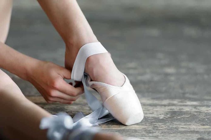 shutterstock_203424955.jpg Ballet dancer tying pointe shoes in a studio