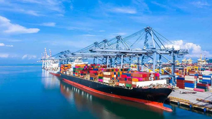 1570847962 Container ship docked at a busy industrial port.