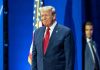 Man in suit next to American flag.