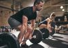Man and woman lifting barbells in gym