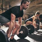 Man and woman lifting barbells in gym
