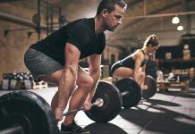 Man and woman lifting barbells in gym