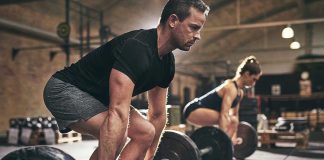 Man and woman lifting barbells in gym