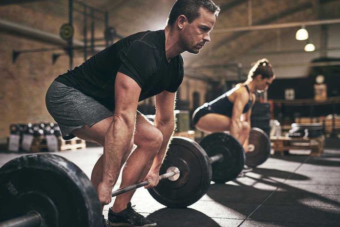 Man and woman lifting barbells in gym
