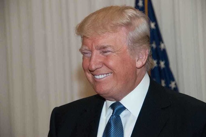 shutterstock_196597007.jpg A smiling man in formal attire with an American flag in the background