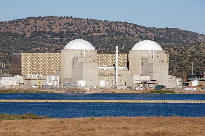 shutterstock_4217311.jpg Nuclear power plant with domed structures beside a water body and mountains in the background