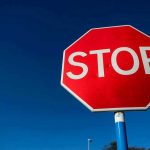 Red stop sign against a clear blue sky.