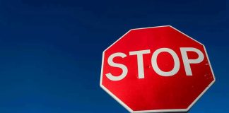Red stop sign against a clear blue sky.